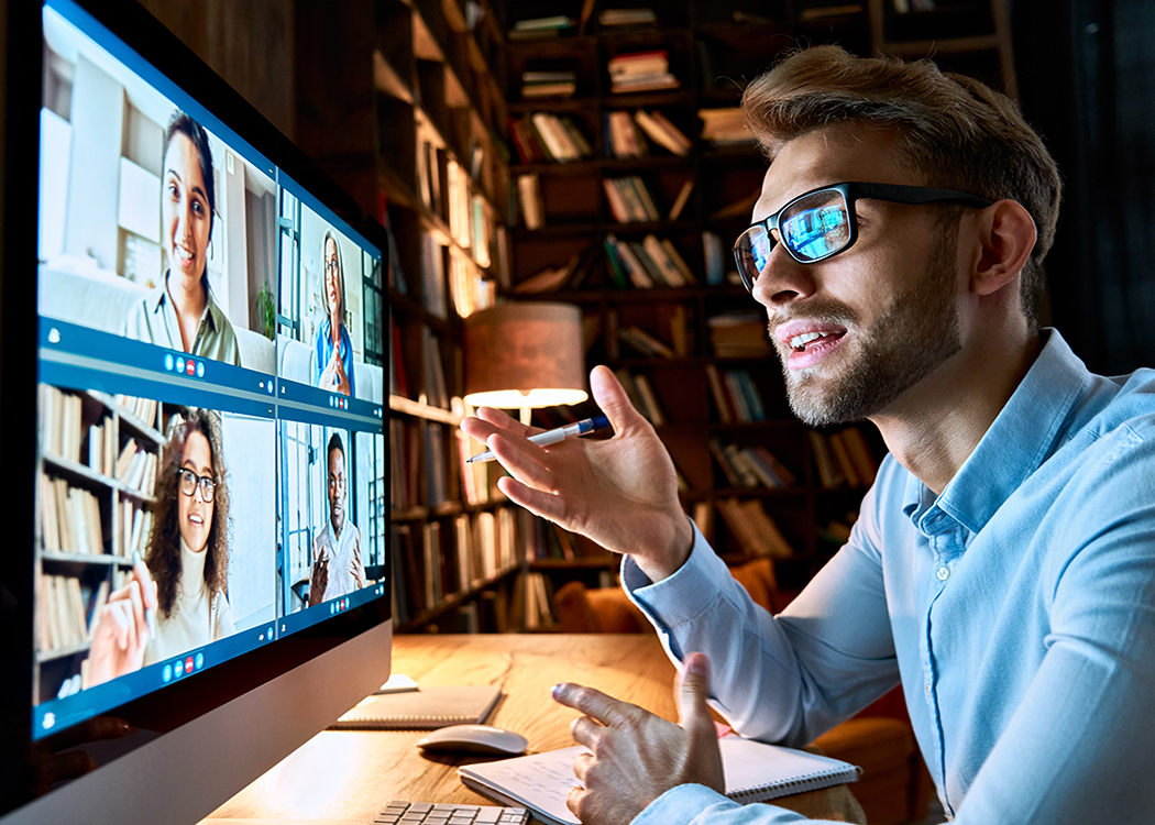 A man in glasses is instructing while pointing at a computer screen.